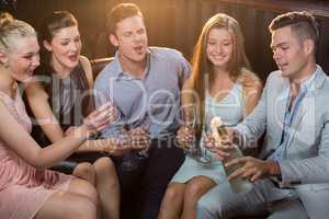 Man popping a champagne bottle while friends watching him