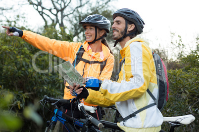 Biker couple with a map pointing in distance
