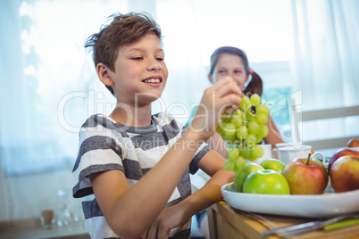 Smiling boy holding a bunch of grapes