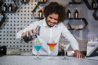 Bartender pouring cocktail into glasses