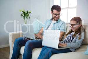 Father and daughter using laptop in the living room