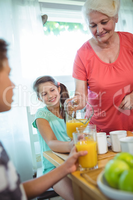 Grandmother pouring orange juice in glass