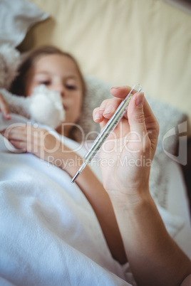 Mother checking daughters temperature on thermometer