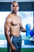 Muscular shirtless athlete holding bottle