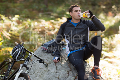 Male biker drinking water in forest