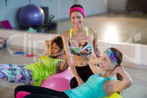 Female trainer assisting woman to exercise on exercise ball