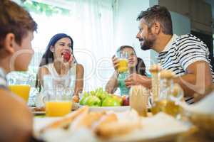 Happy family talking to each other while having breakfast together
