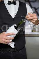 Bartender using corkscrew to open wine bottle