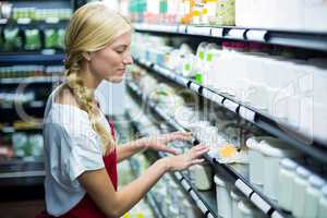 Female staff checking grocery products in shelf