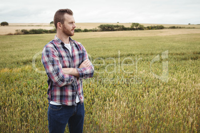 Portrait of farmer standing with arms crossed in the field