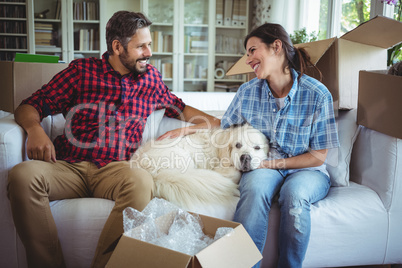 Couple sitting on sofa with their pet dog