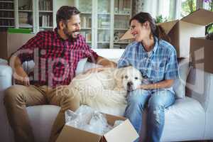 Couple sitting on sofa with their pet dog