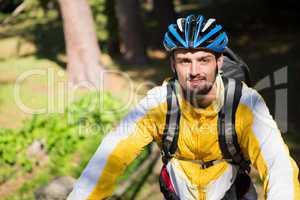 Portrait of male mountain biker with bicycle in the forest