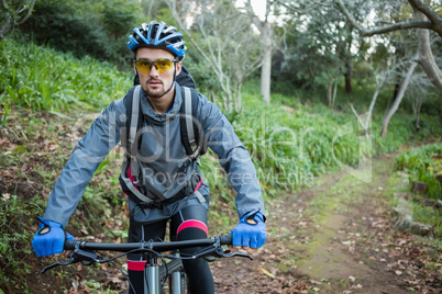 Portrait of male mountain biker with bicycle in the forest