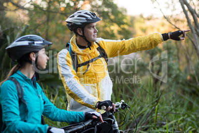 Biker couple with mountain bike pointing in distance