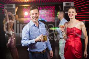 Smiling couple holding glass of beer and cocktail while dancing