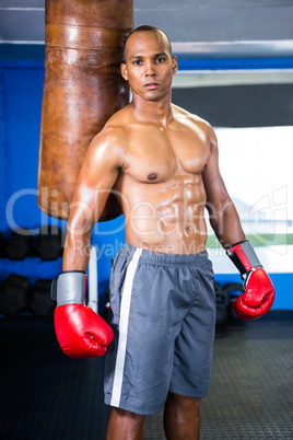 Determined male boxer standing by punching bag