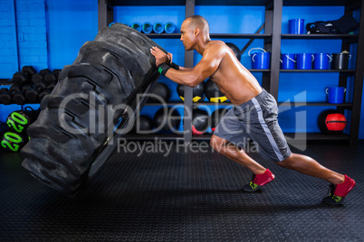 Side view of male athlete pushing tire