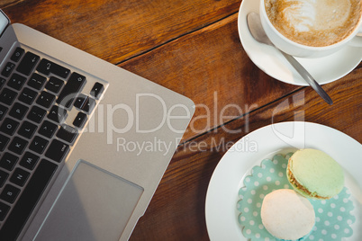 Cappuccino, laptop and sweet food on table
