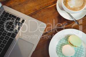 Cappuccino, laptop and sweet food on table