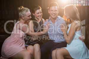 Smiling friends sitting together in sofa