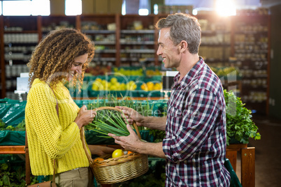 Happy couple buying vegetables in organic section