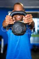 Man covering face with kettlebell in gym