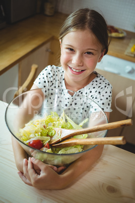 Girl holding a bowl of salad in kitchen