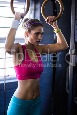 Serious woman holding gymnastic rings in gym