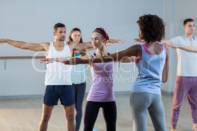 Yoga instructor helping student with a correct pose