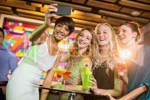 Group of friends taking selfie from mobile phone while having cocktail