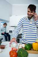 Father talking on mobile phone while working in the kitchen