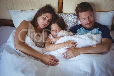 Family sleeping on bed