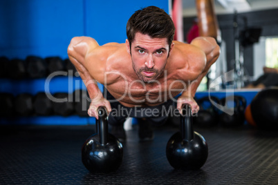 Shirtless athlete exercising with kettlebells