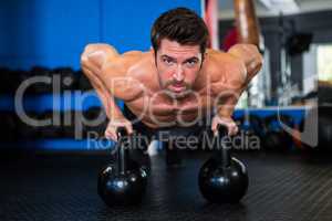 Shirtless athlete exercising with kettlebells