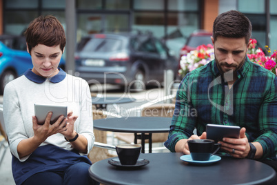 Businesspeople using digital tablet while having coffee