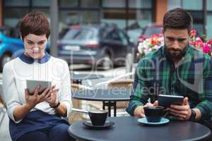 Businesspeople using digital tablet while having coffee