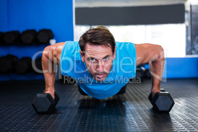 Serious athlete doing push-ups with dumbbells