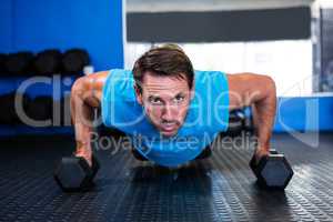 Serious athlete doing push-ups with dumbbells