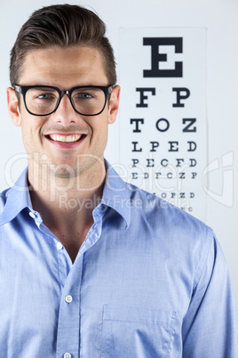 Man wearing spectacles with eye chart in background
