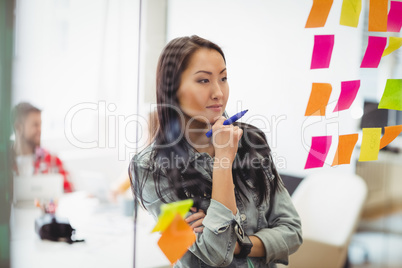 Female photo editor looking at multi colored sticky notes