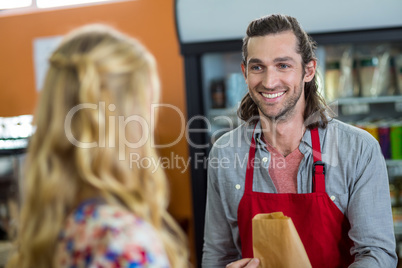 Male staff interacting with woman in supermarket