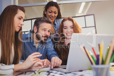 Businesswomen with male coworker using laptop at desk Businesswomen with male coworker using laptop at desk