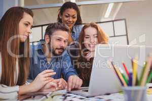 Businesswomen with male coworker using laptop at desk