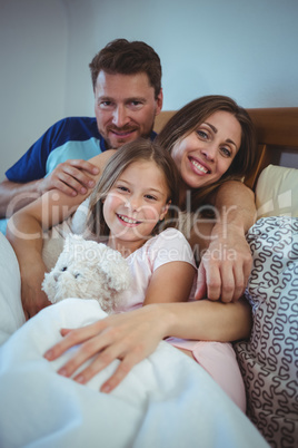 Parents lying on bed with daughter