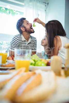 Woman feeding grapes to man while having breakfast