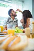 Woman feeding grapes to man while having breakfast