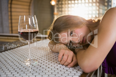 Woman lying on bar counter with wine glass on table