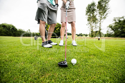 Male instructor assisting woman in learning golf