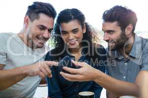 Three friends using mobile phone in the coffee shop